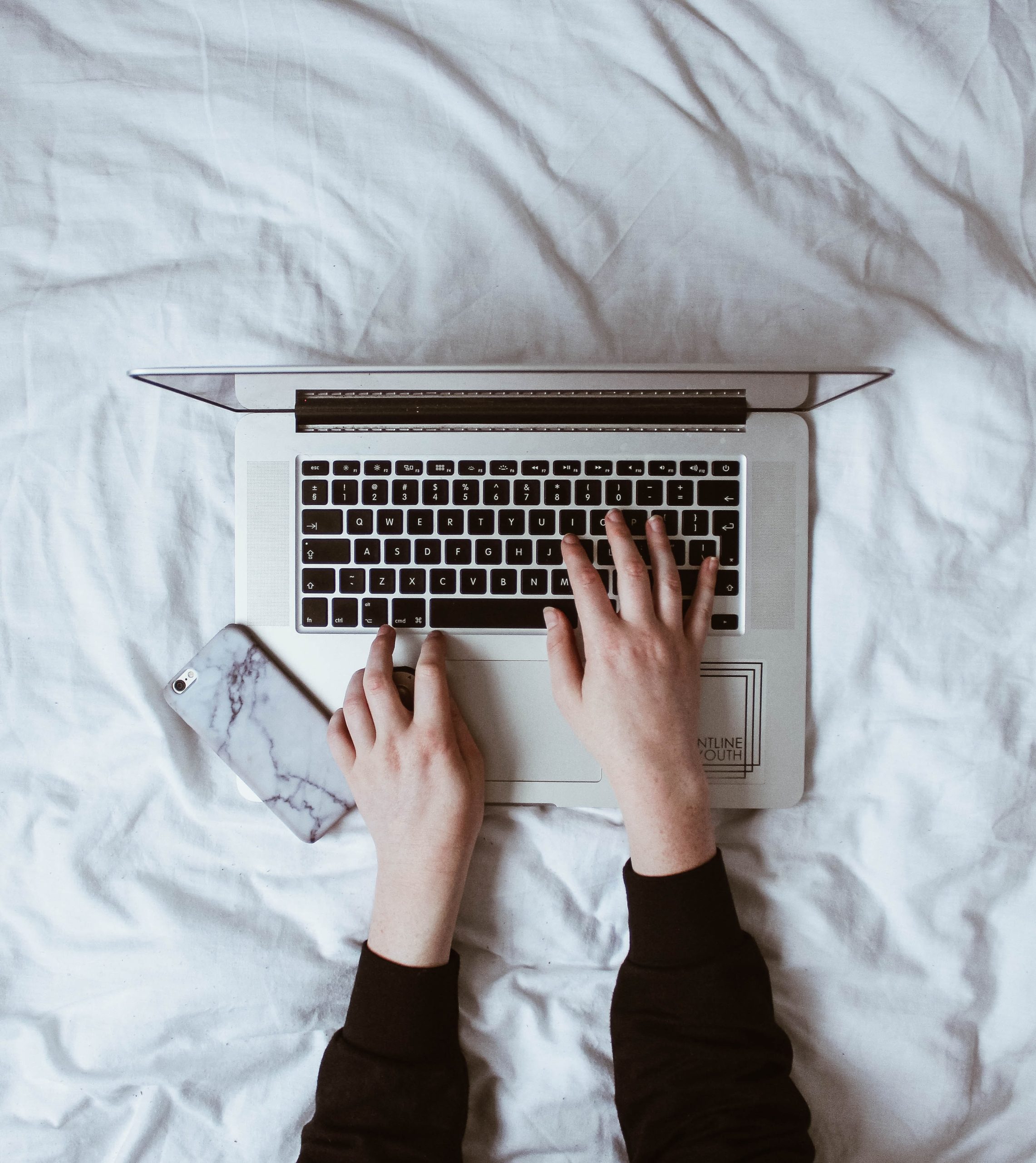 Computadora y teléfono sobre una cama para trabajar